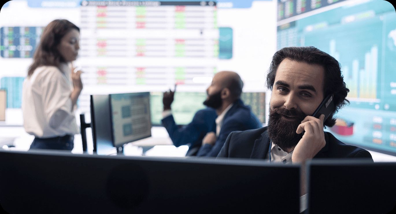 Tradier team members at work on a trading floor, surrounded by screens of live market data